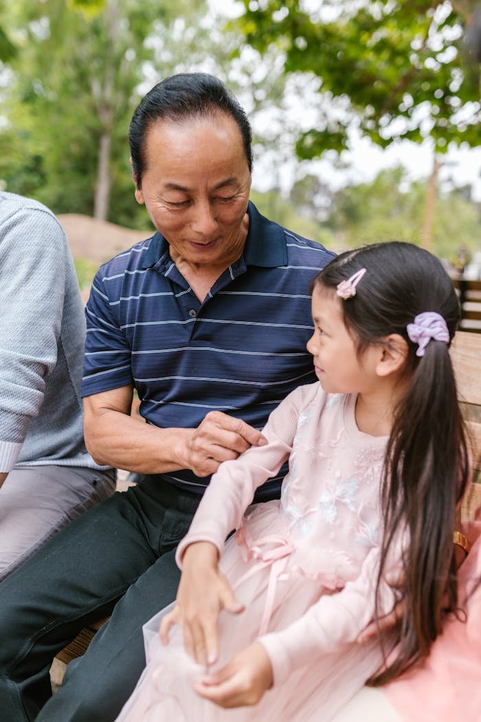 An affectionate moment between a grandfather and granddaughter enjoying time outdoors.